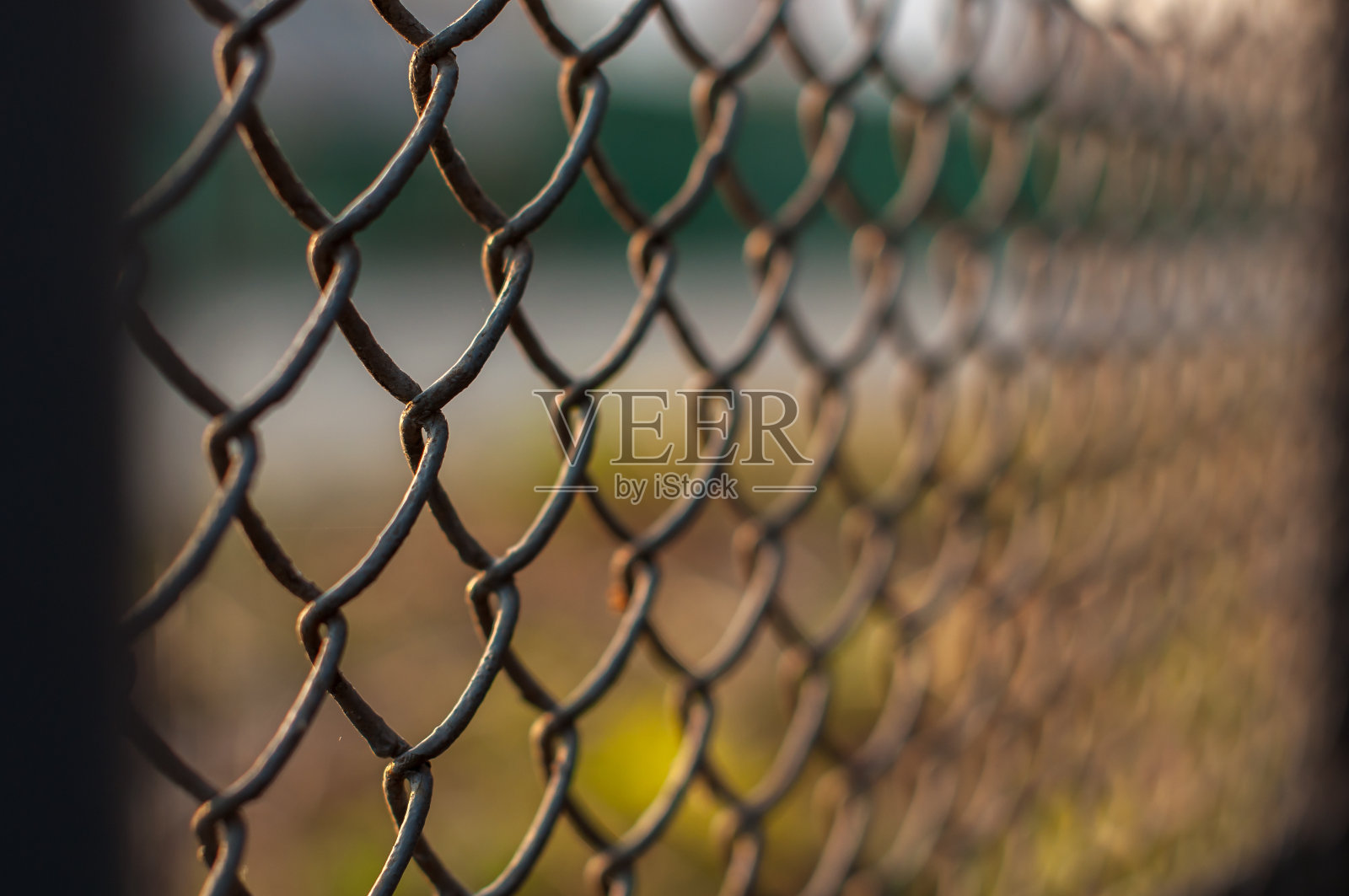 透过铁丝网围栏俯瞰城市的日落，特写镜头照片摄影图片