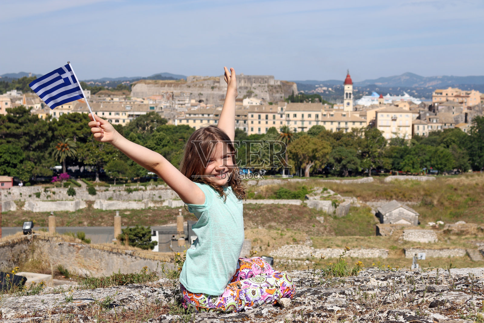 快乐的小女孩挥舞着希腊科孚镇的国旗照片摄影图片