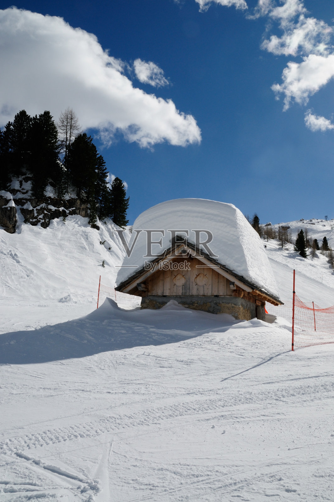阿尔卑斯山上的Alpin小屋，屋顶上有很多雪。意大利威尼托Falzarego山口附近的冬季景观照片摄影图片
