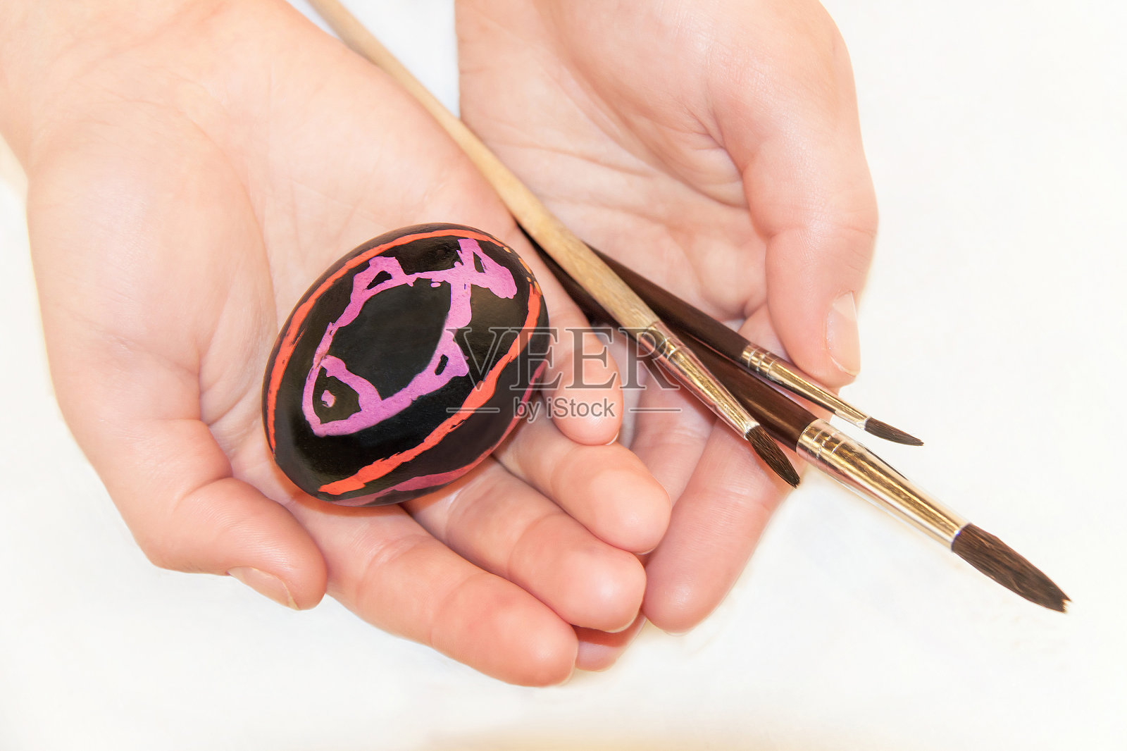 手上拿着复活节彩蛋和画笔。照片摄影图片