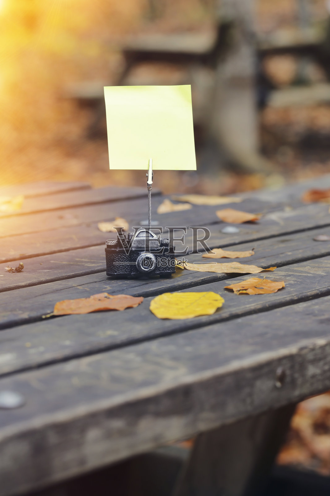 空白纸贴纸与秋天的树叶在老木头的背景。户外复古的金钥匙照片摄影图片