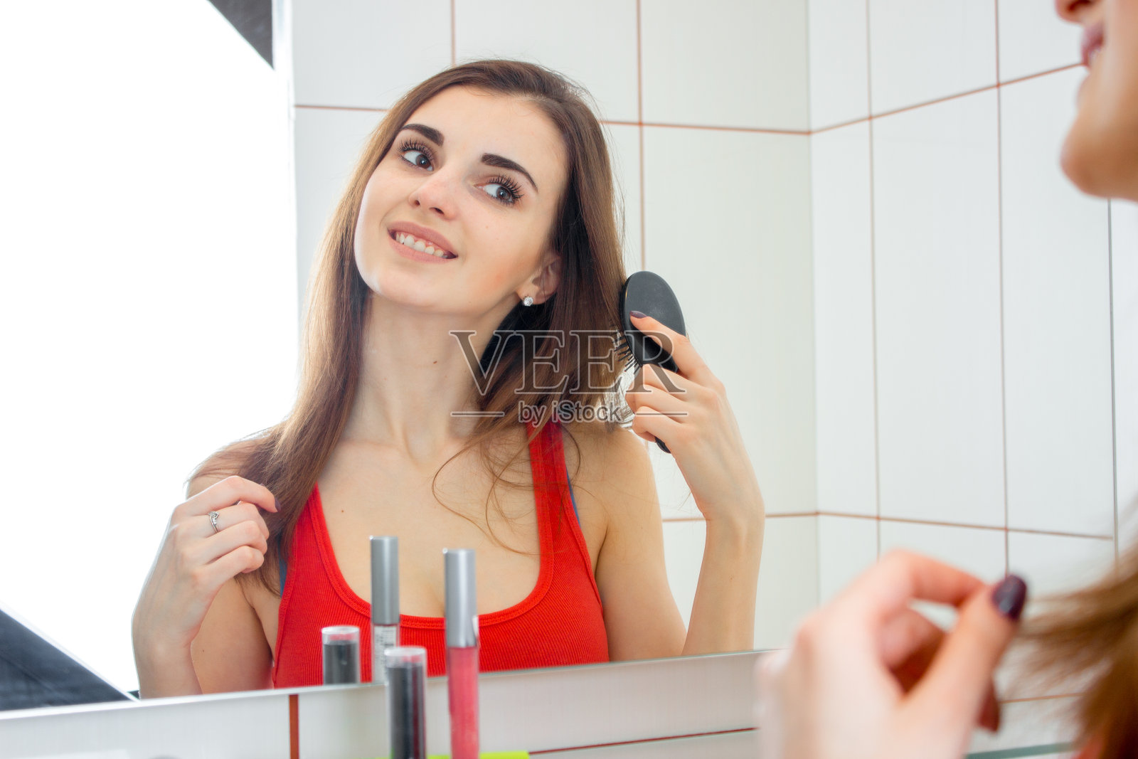 可爱的微笑女孩穿着红色背心站在浴室的镜子前照片摄影图片