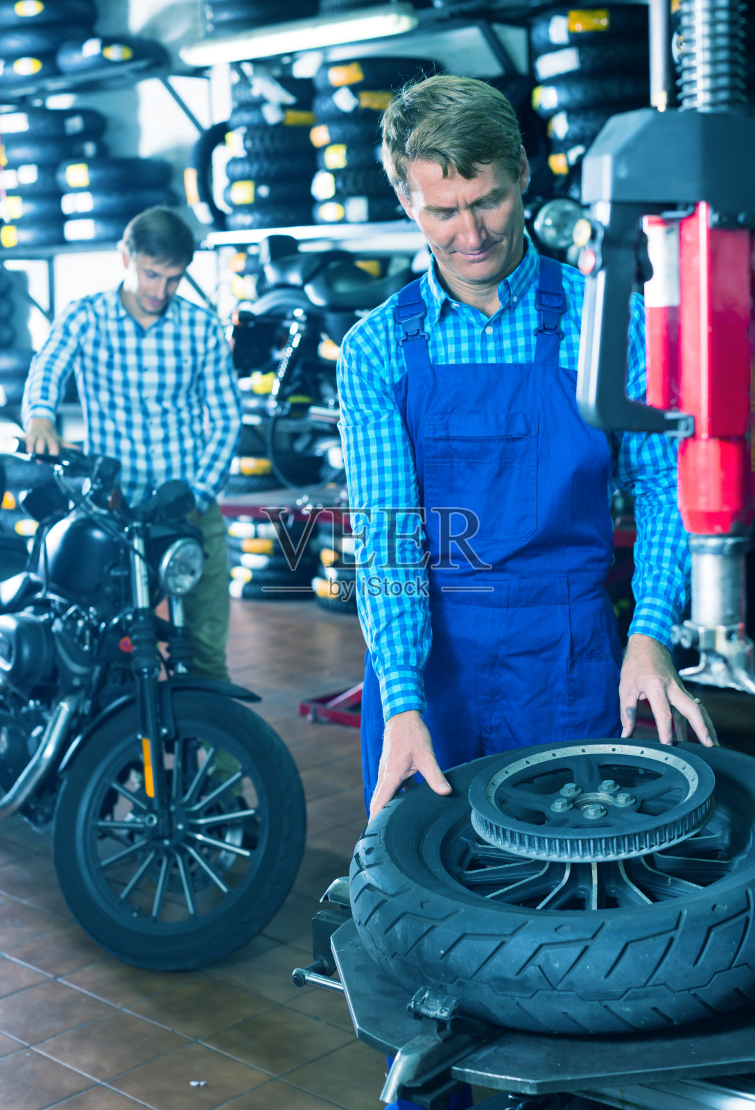 车间里带着自行车轮的机械师照片摄影图片