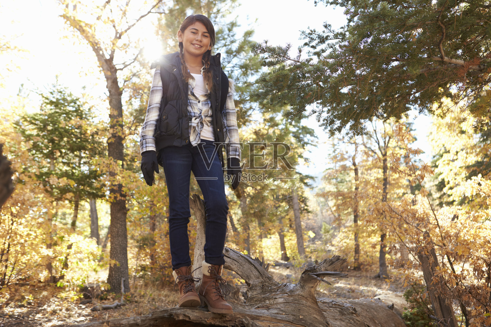 一个西班牙女孩站在森林里倒下的树上照片摄影图片