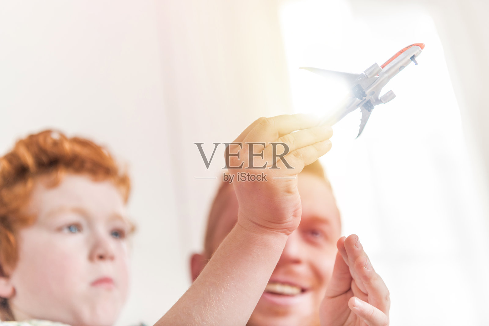 父子俩笑着在家里玩玩具飞机照片摄影图片