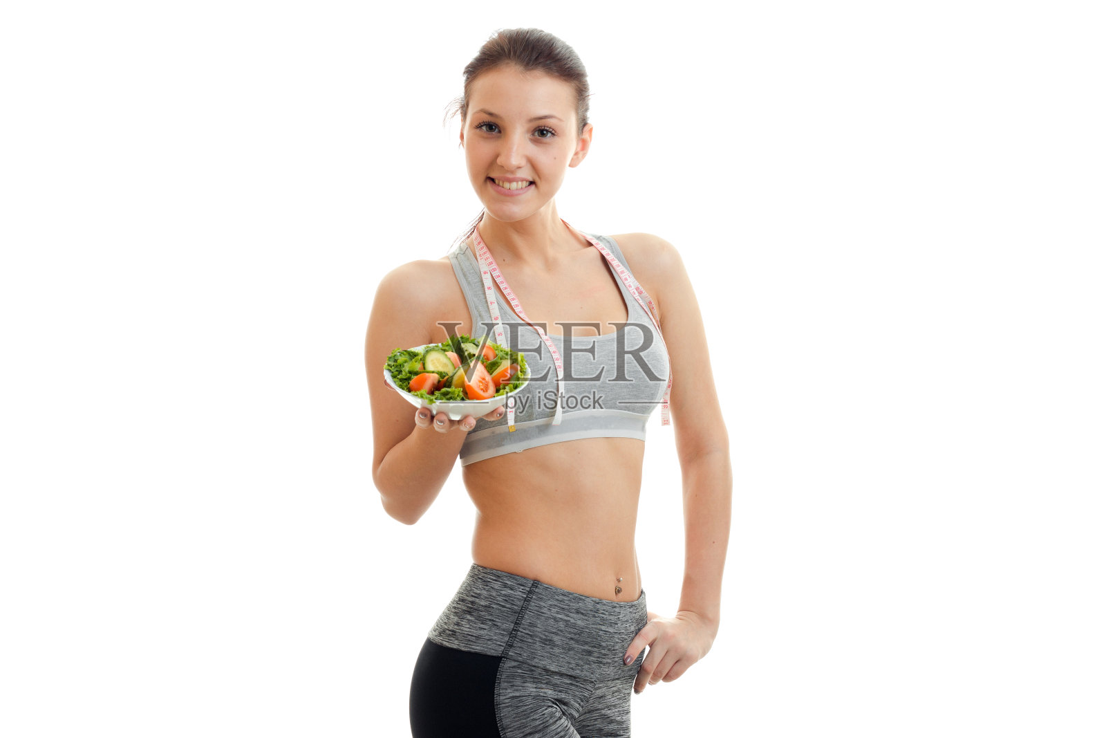 苗条迷人的年轻女孩拿着蔬菜沙拉，微笑着照片摄影图片