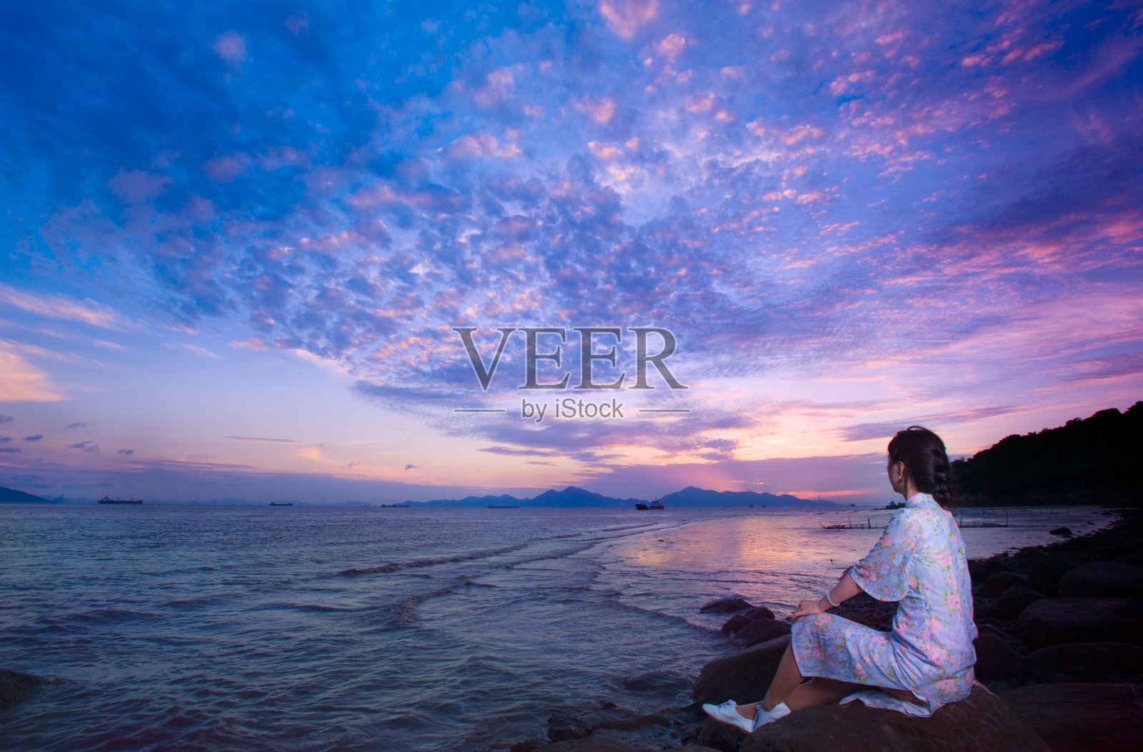 穿着旗袍坐在海滩上的女人照片摄影图片