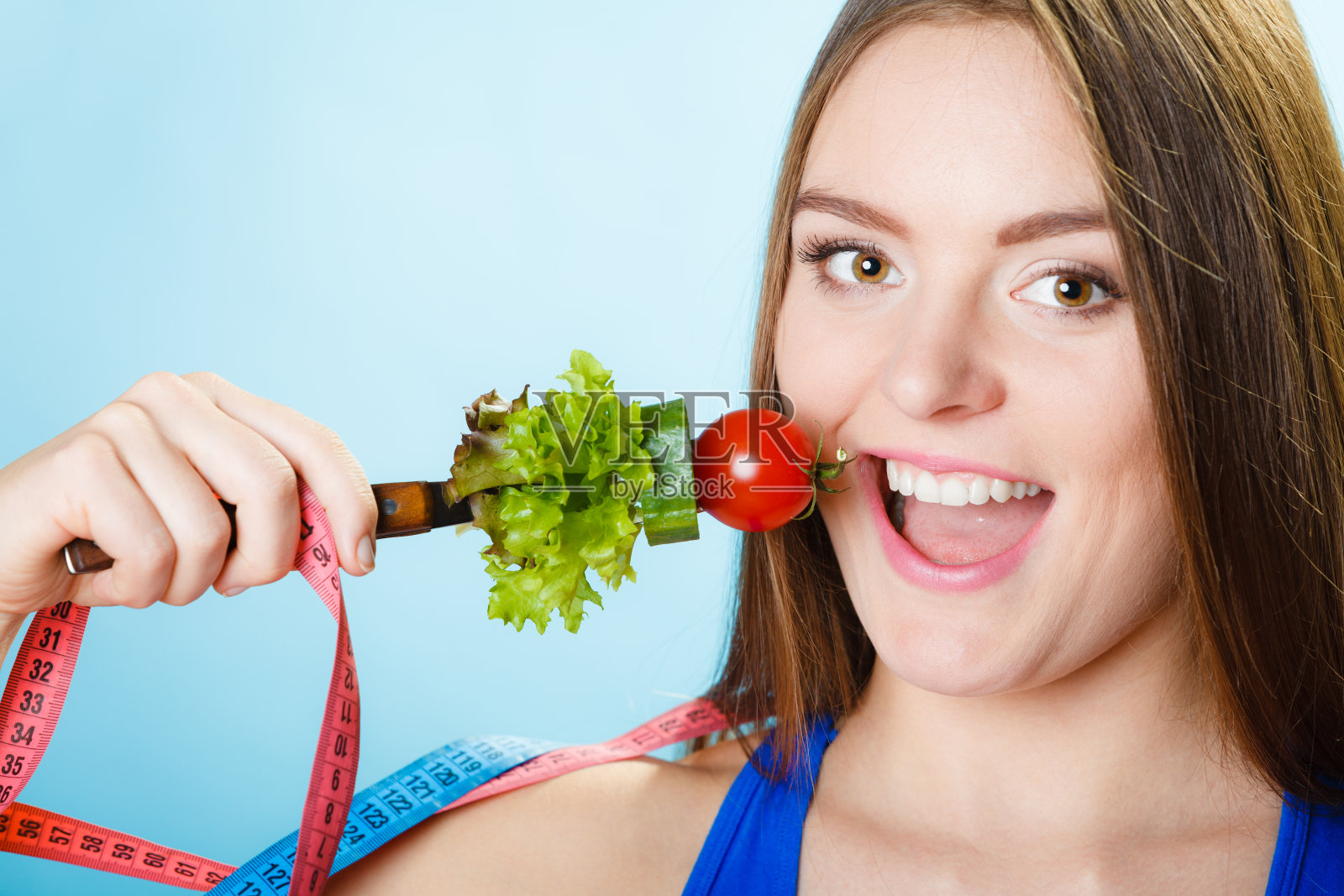 拿着素食和卷尺的女人。照片摄影图片