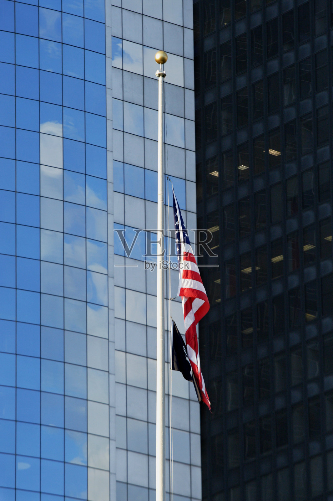 美国国旗对着现代摩天大楼降半旗照片摄影图片