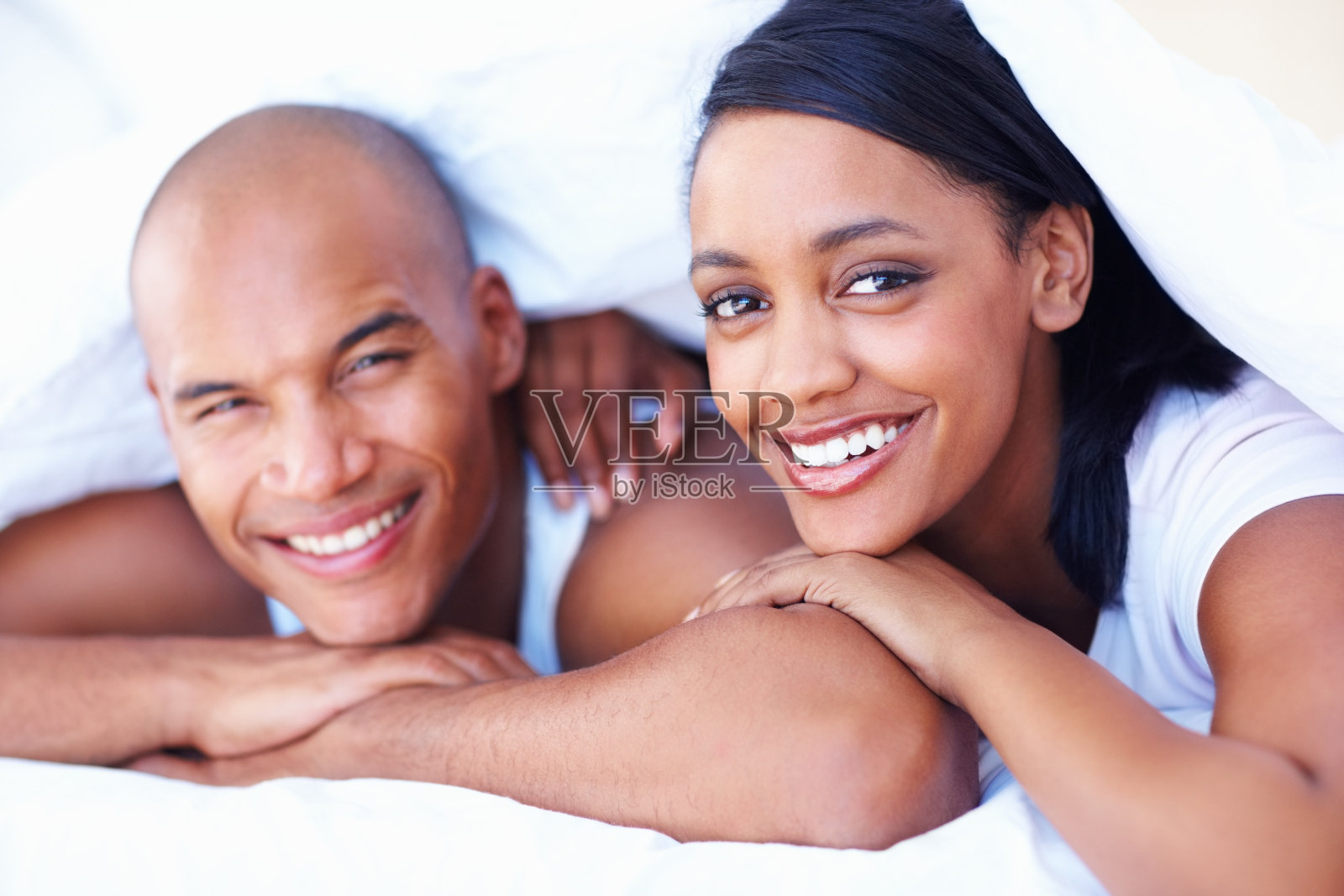 微笑的年轻夫妇躺在床上照片摄影图片