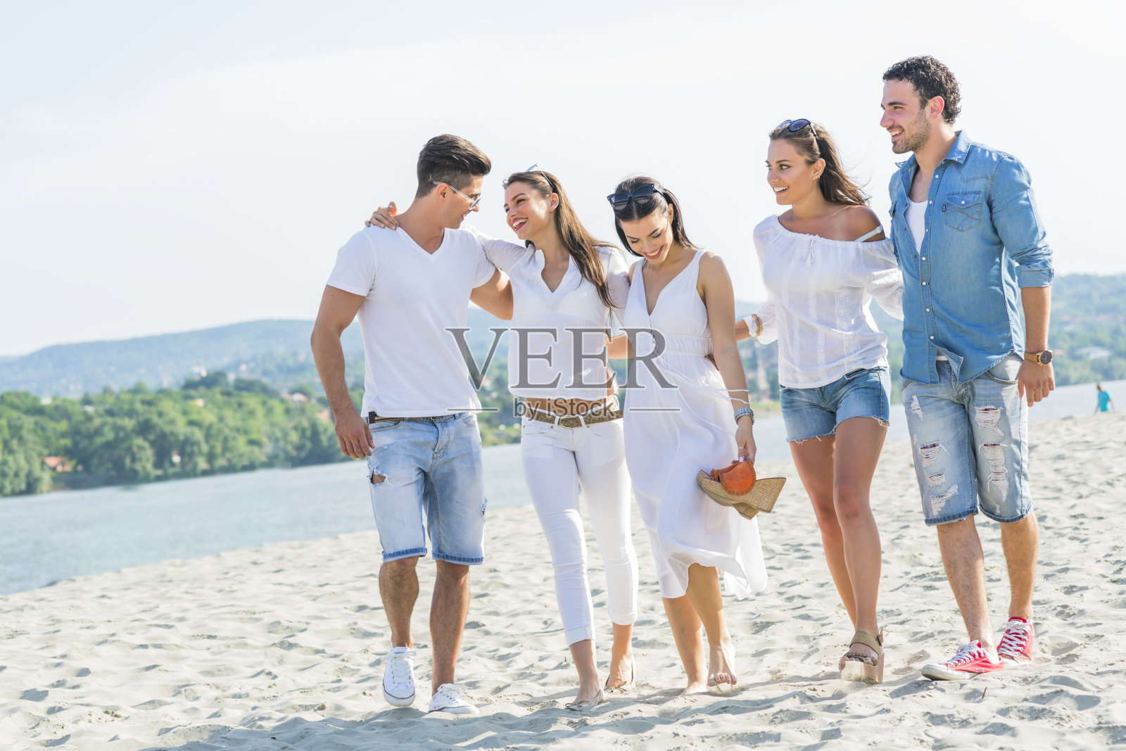 一群年轻人手牵着手在海滩上照片摄影图片