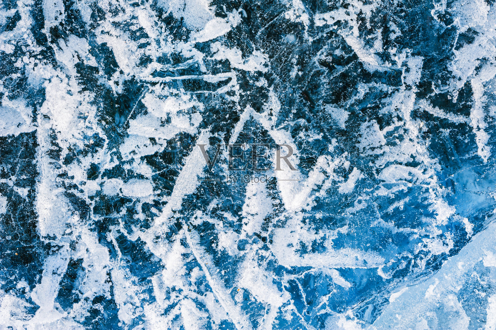 结冰的湖面上有裂缝和气泡的蓝色冰。照片摄影图片