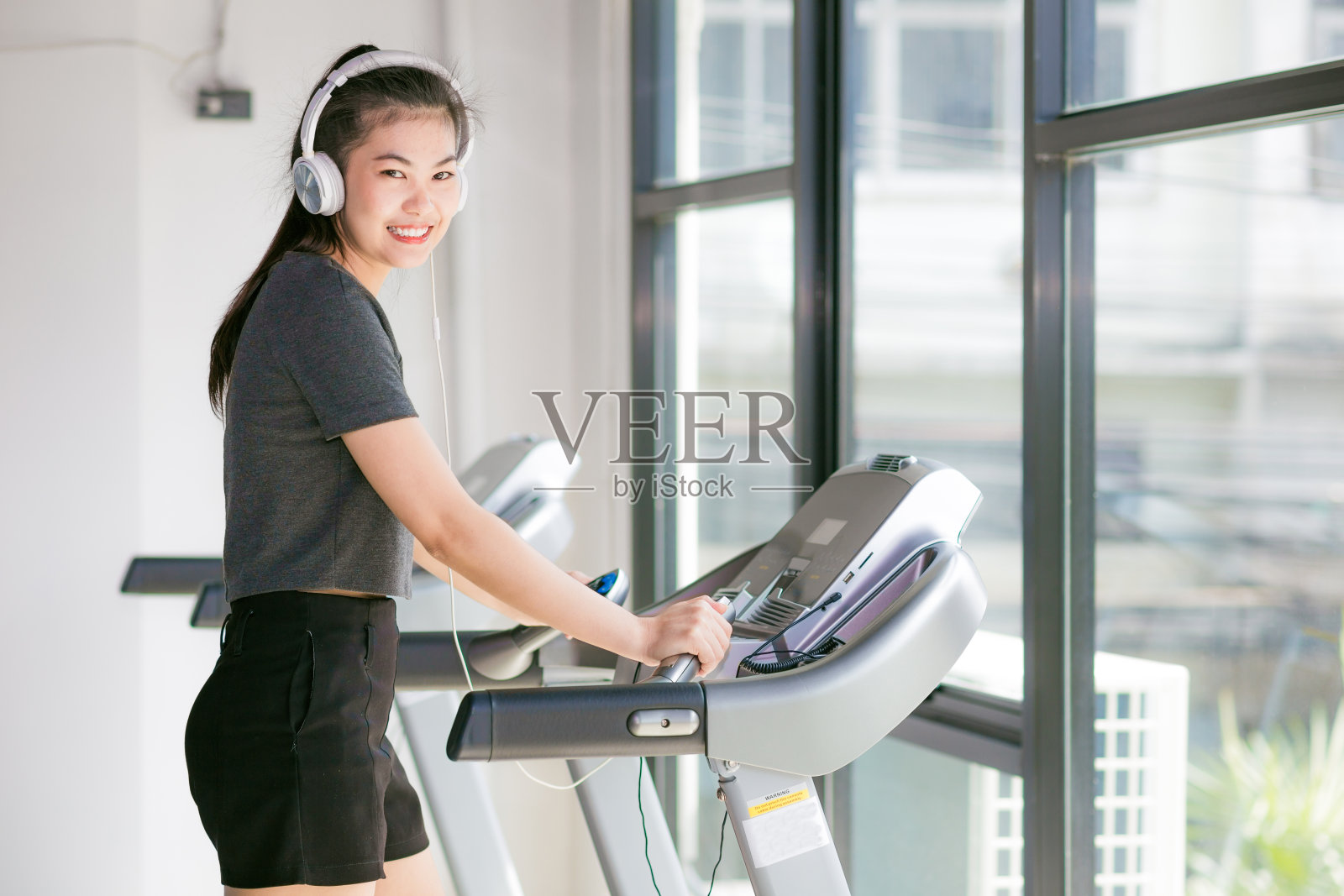 亚洲妇女在健身房锻炼在一个交叉教练照片摄影图片