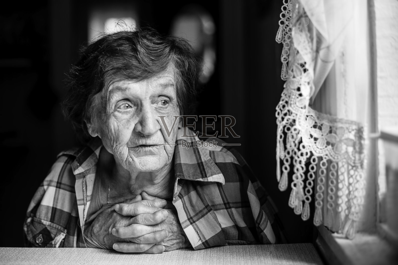 一位上了年纪的妇女靠近窗户。照片摄影图片