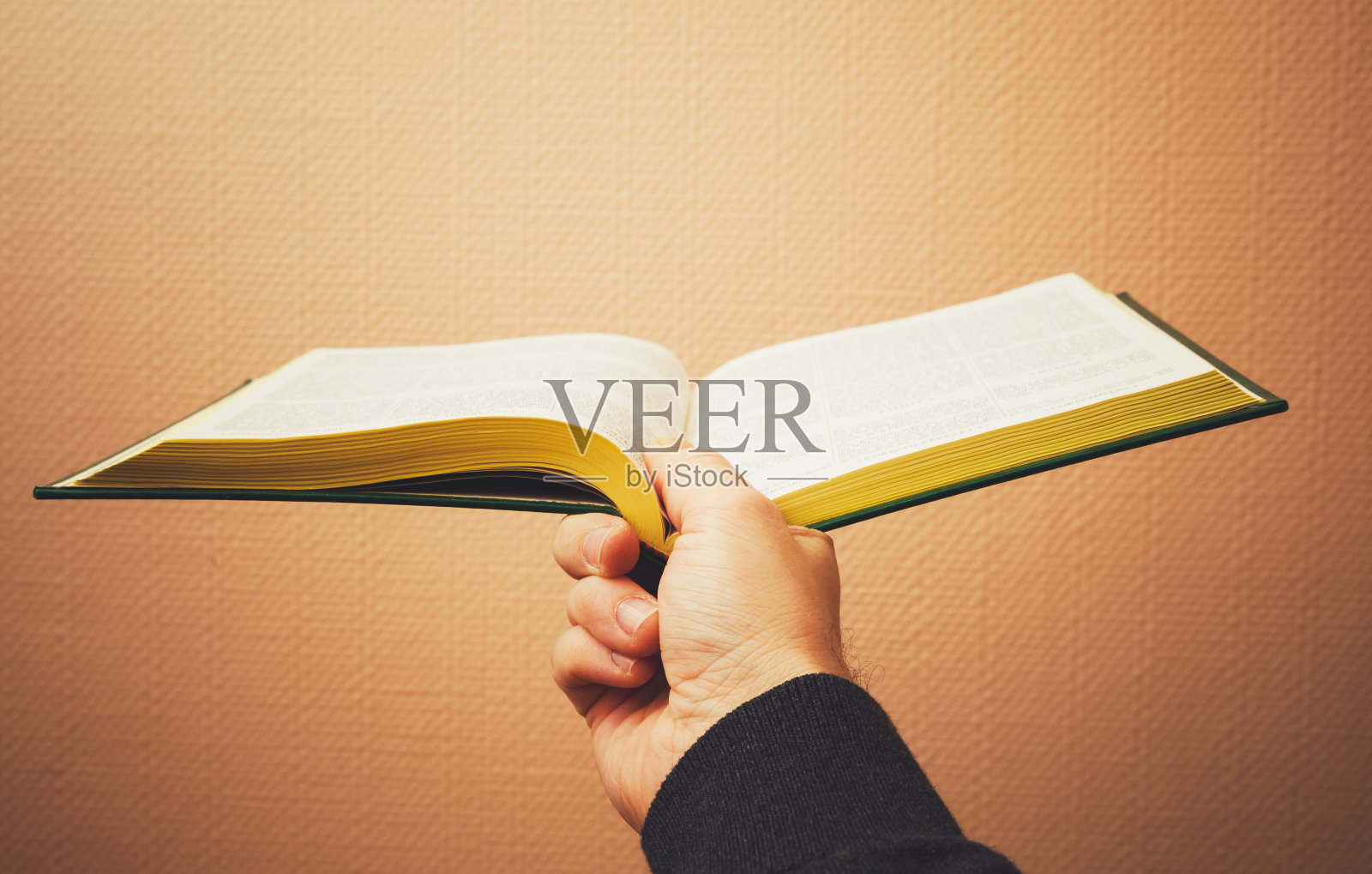 男性手持打开的书，复古色调照片摄影图片