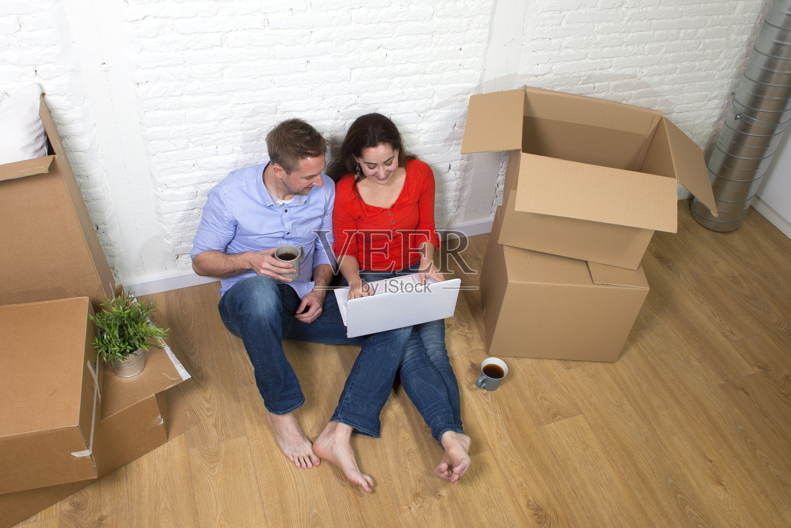 一对夫妇坐在地板上移动在新房子公寓公寓照片摄影图片