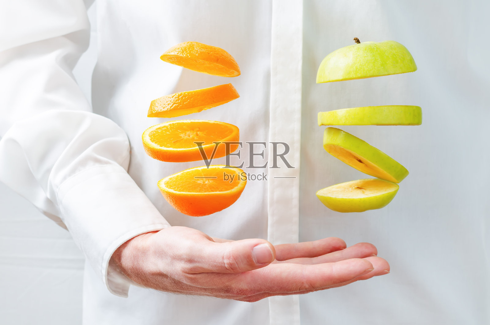 男人的手握着飞飞的橘子和苹果照片摄影图片