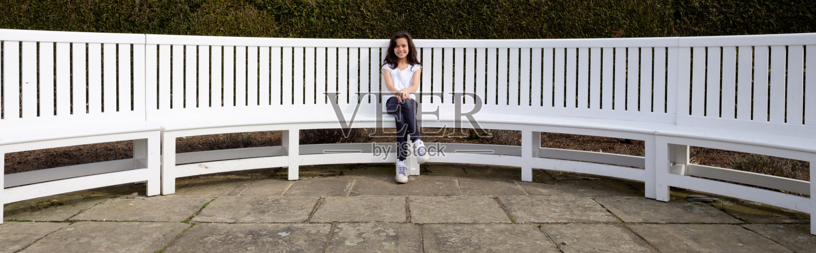 女孩坐在长长的白色长凳上照片摄影图片