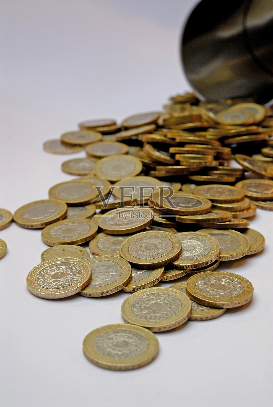 两英镑硬币从储蓄罐里洒了出来照片摄影图片