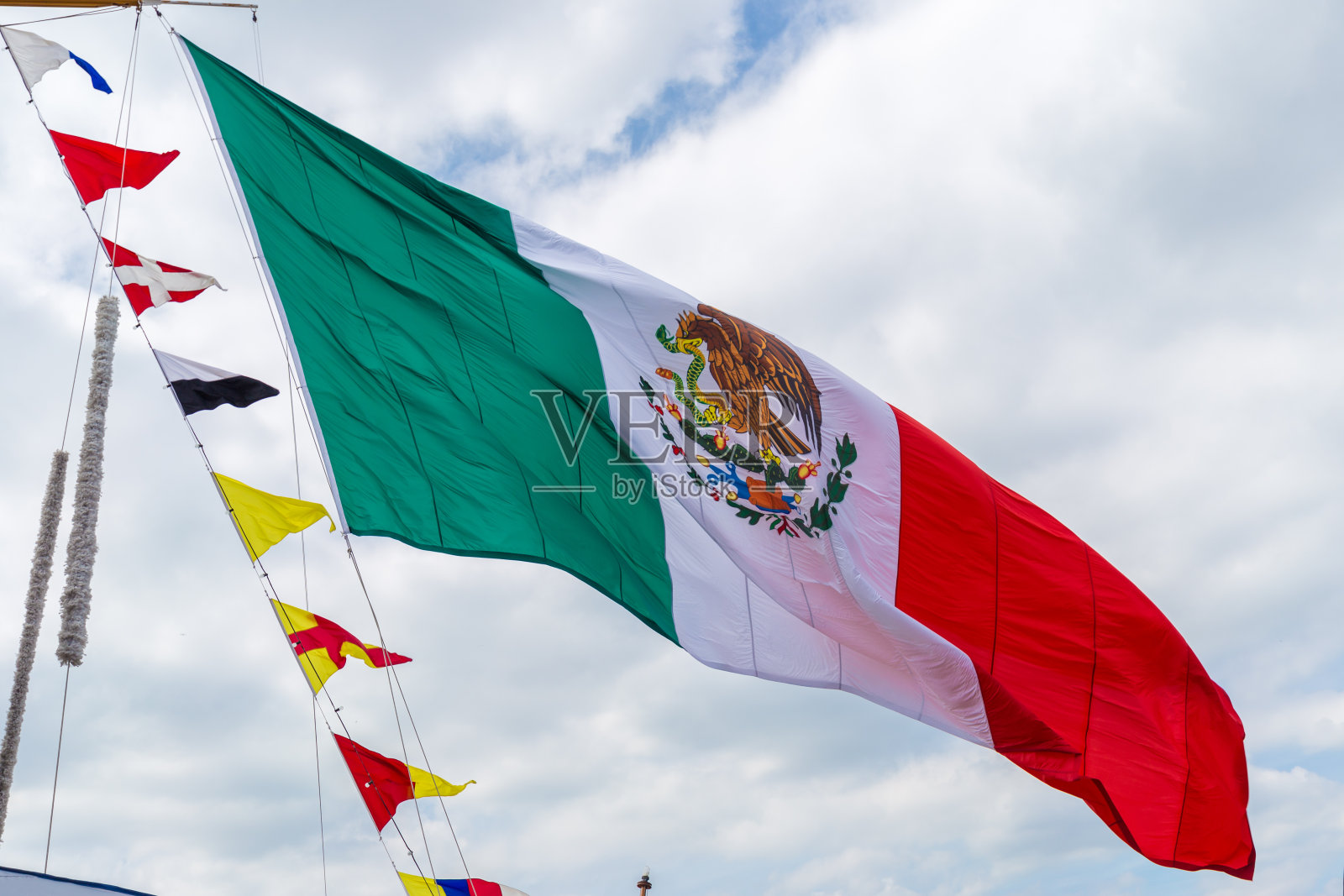 巨大的墨西哥国旗在天空背景中编织照片摄影图片