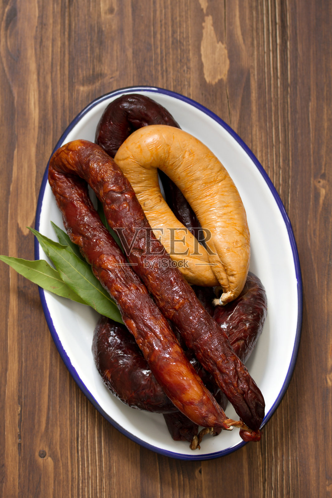 熏香肠放在白色的盘子上，棕色的木制背景照片摄影图片