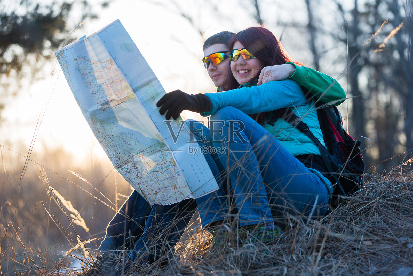 一对夫妇坐在草地上看地图。照片摄影图片