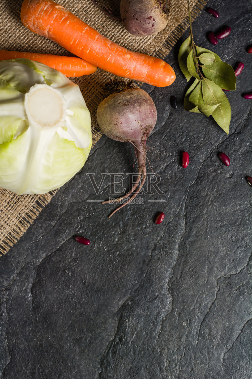 烹饪时食用甜菜、胡萝卜和卷心菜。深色背景上的构图。照片摄影图片