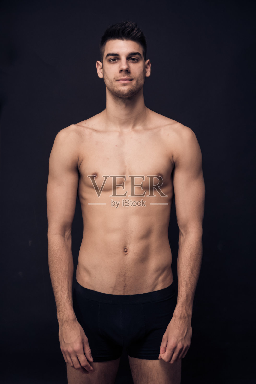 一个年轻人赤裸着上身，看着镜头照片摄影图片