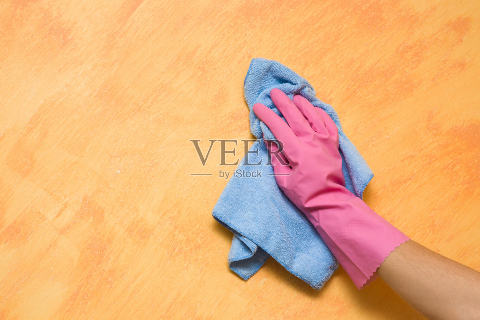 手戴粉红色防护手套，用抹布擦拭墙面。早春大扫除或定期大扫除。女保洁员打扫房子。照片摄影图片