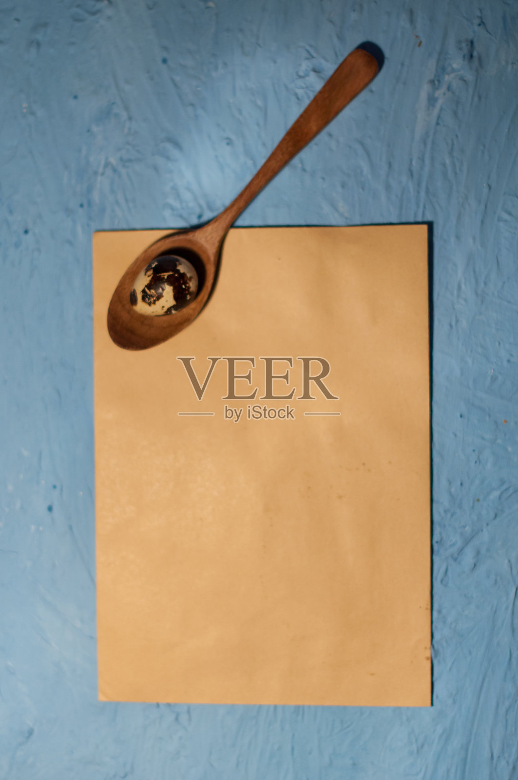 鹌鹑蛋在木汤匙和蓝色纹理的背景照片摄影图片