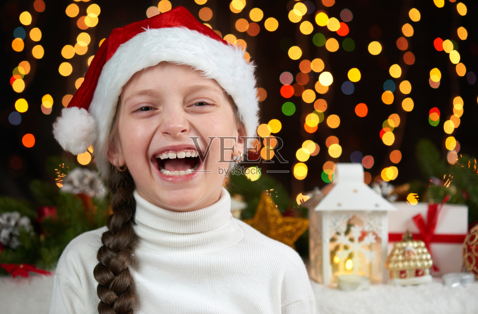 儿童女孩肖像在黑色的背景上装饰圣诞节，脸上表情和快乐的情绪，穿着圣诞老人的帽子，冬季假期的概念照片摄影图片