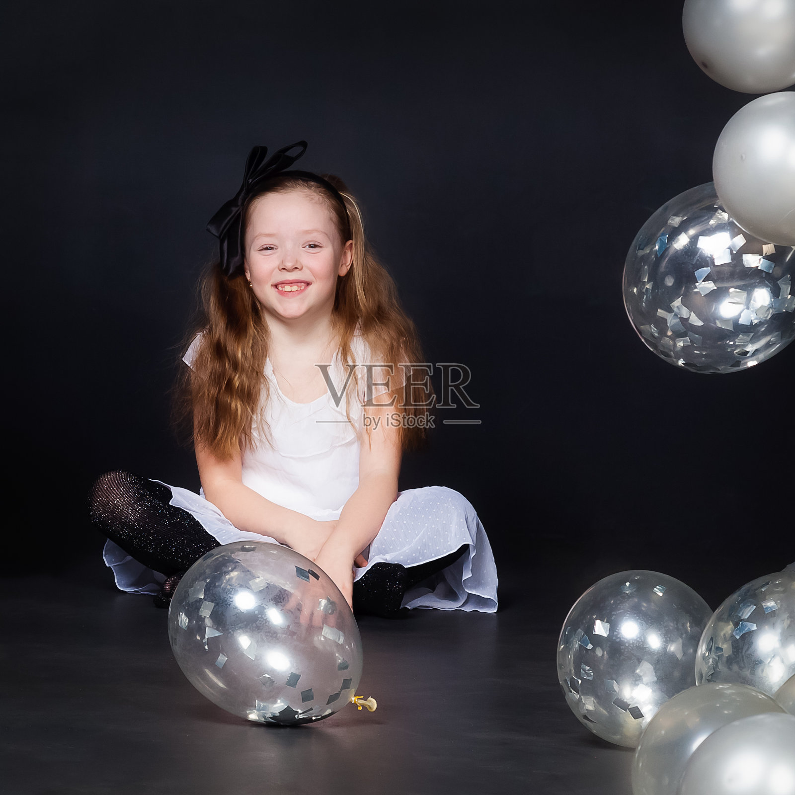 女孩拿着气球坐在地板上照片摄影图片