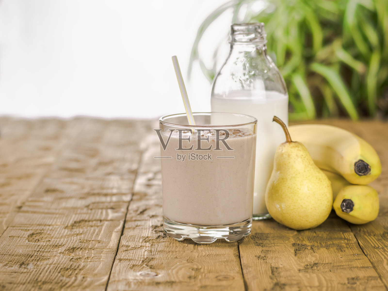 木桌上放着香蕉奶昔、巧克力、梨和牛奶。照片摄影图片