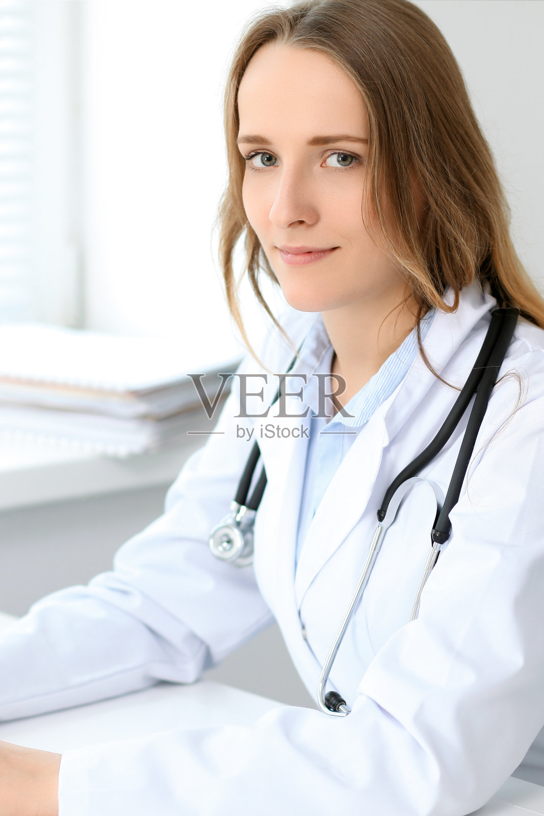 年轻貌美的女医生坐在医院靠窗的那张桌子旁照片摄影图片