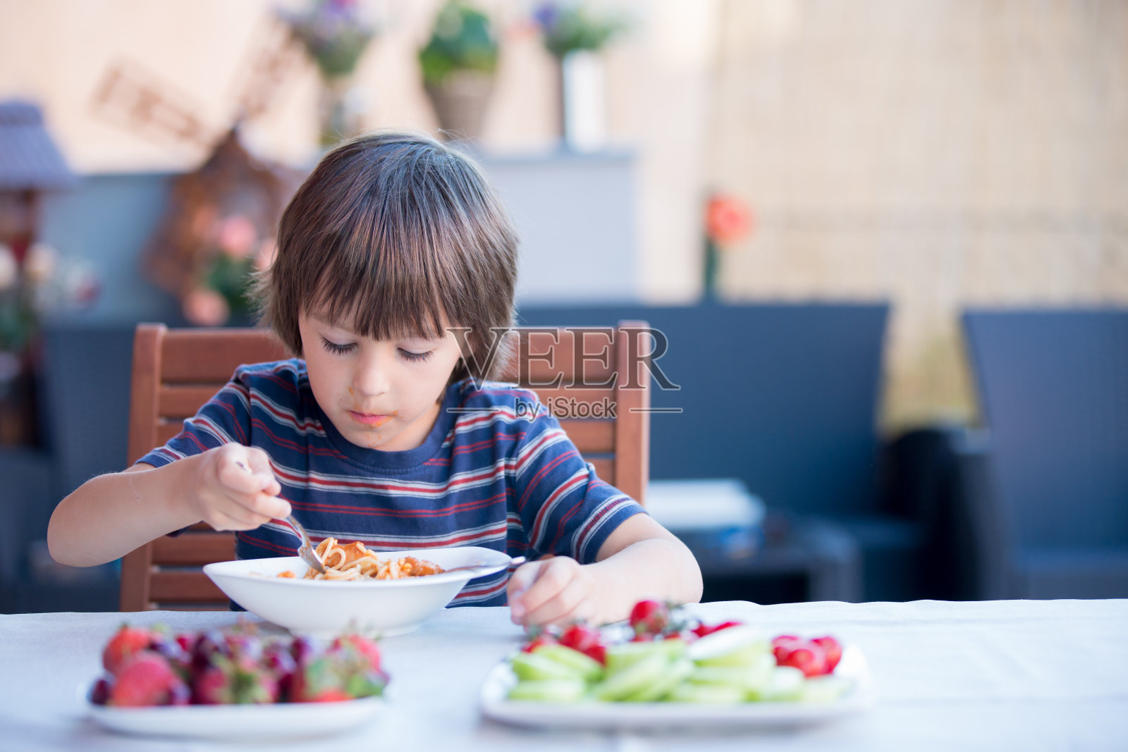 可爱的孩子，学前班的小男孩，午餐在户外吃意大利面照片摄影图片