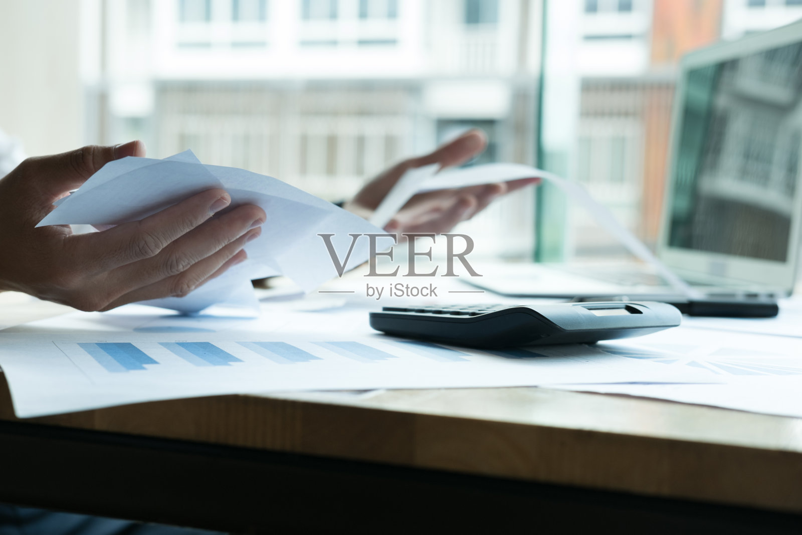 男人在家计算家庭账单。在办公室使用计算器的商人。年轻的男性检查平衡和成本。开始计算财务。为纳税做文书工作的商人照片摄影图片