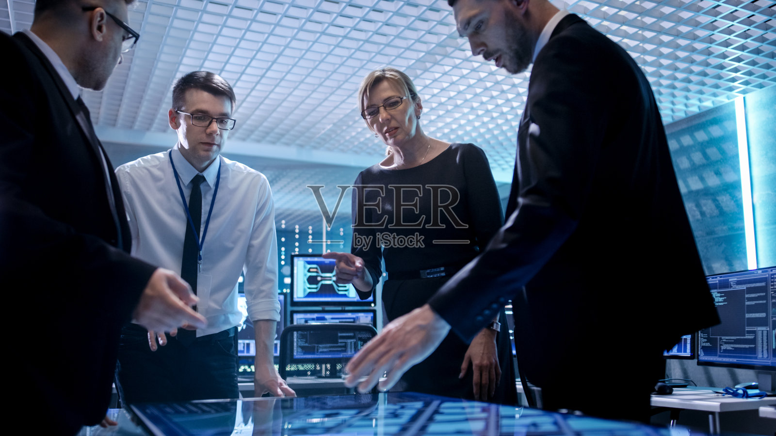 公司经理团队在监控室的桌子上工作。他们在最先进的设备里。电脑有动画屏幕。照片摄影图片