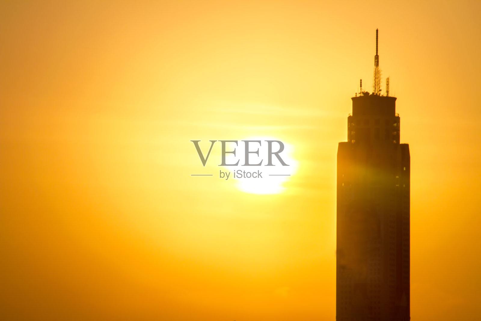 夕阳西下，城市里建着传输塔照片摄影图片