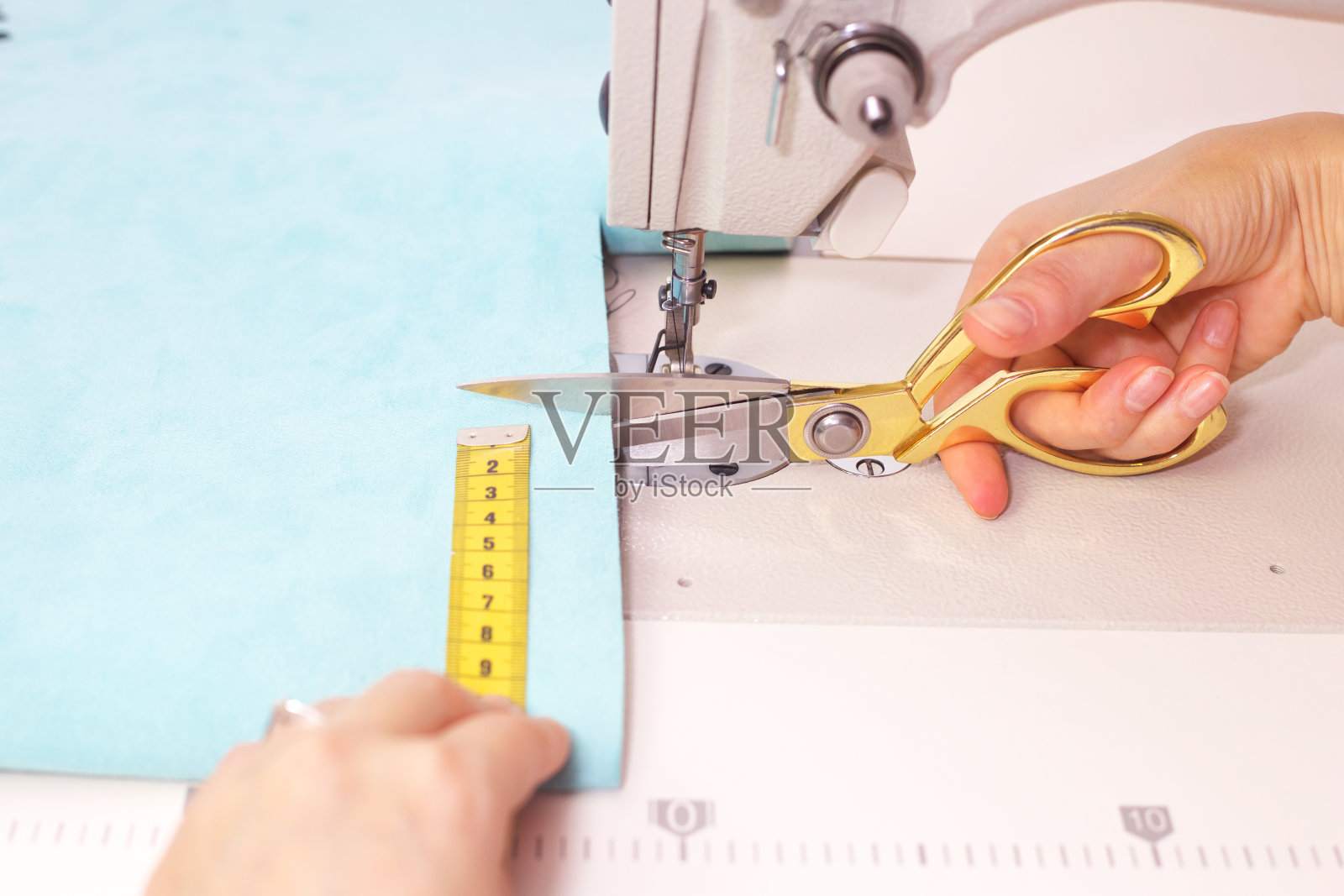 裁缝测量和裁剪纺织材料。照片摄影图片