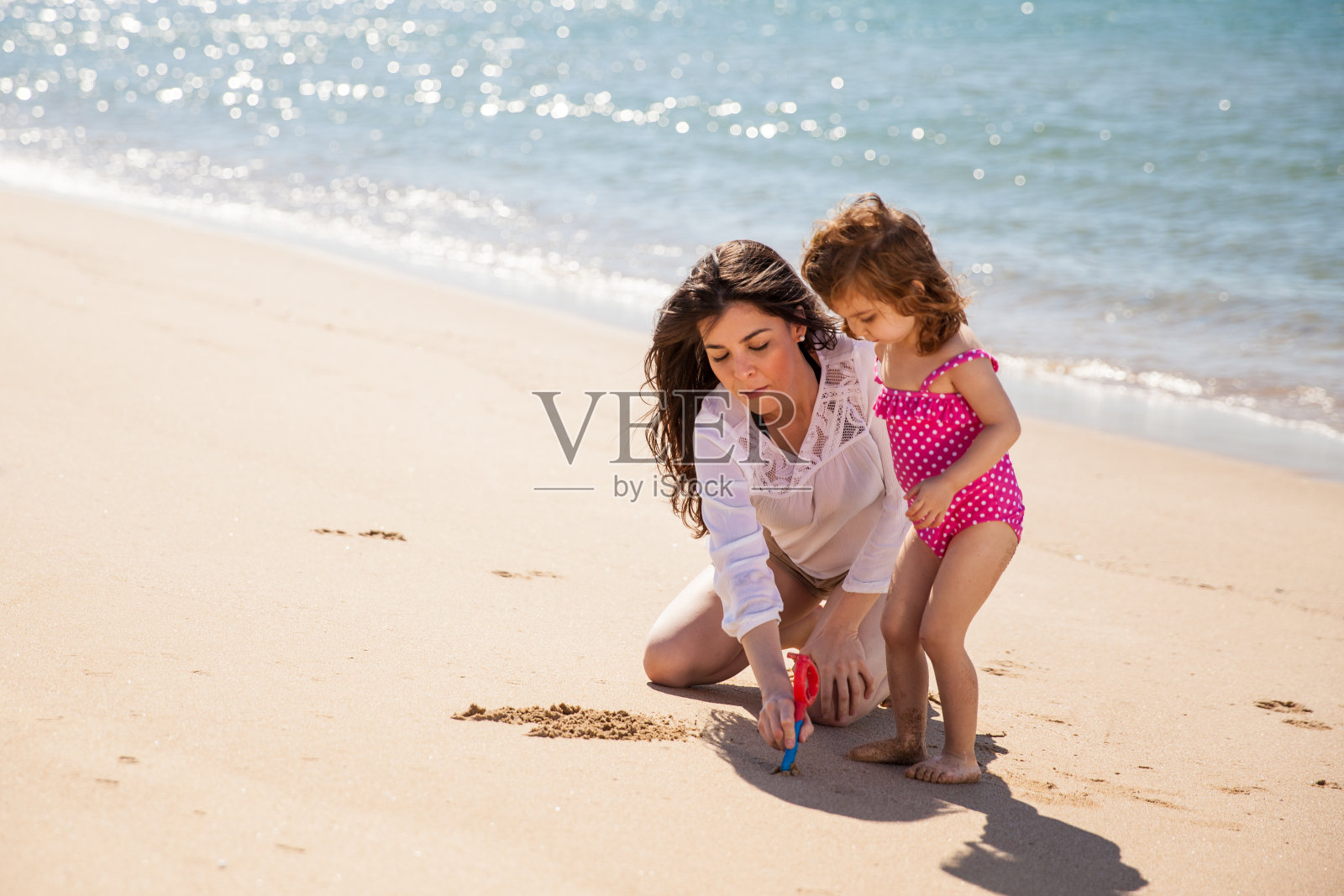 妈妈和女儿在沙子上写字照片摄影图片