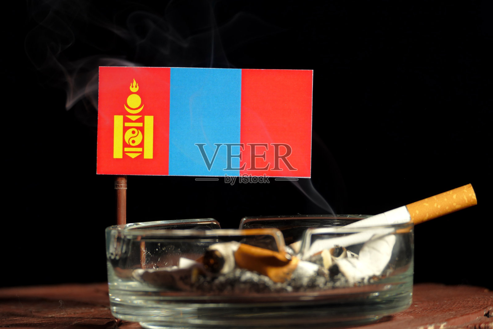 蒙古国旗和燃烧的香烟烟灰缸孤立在黑色的背景照片摄影图片