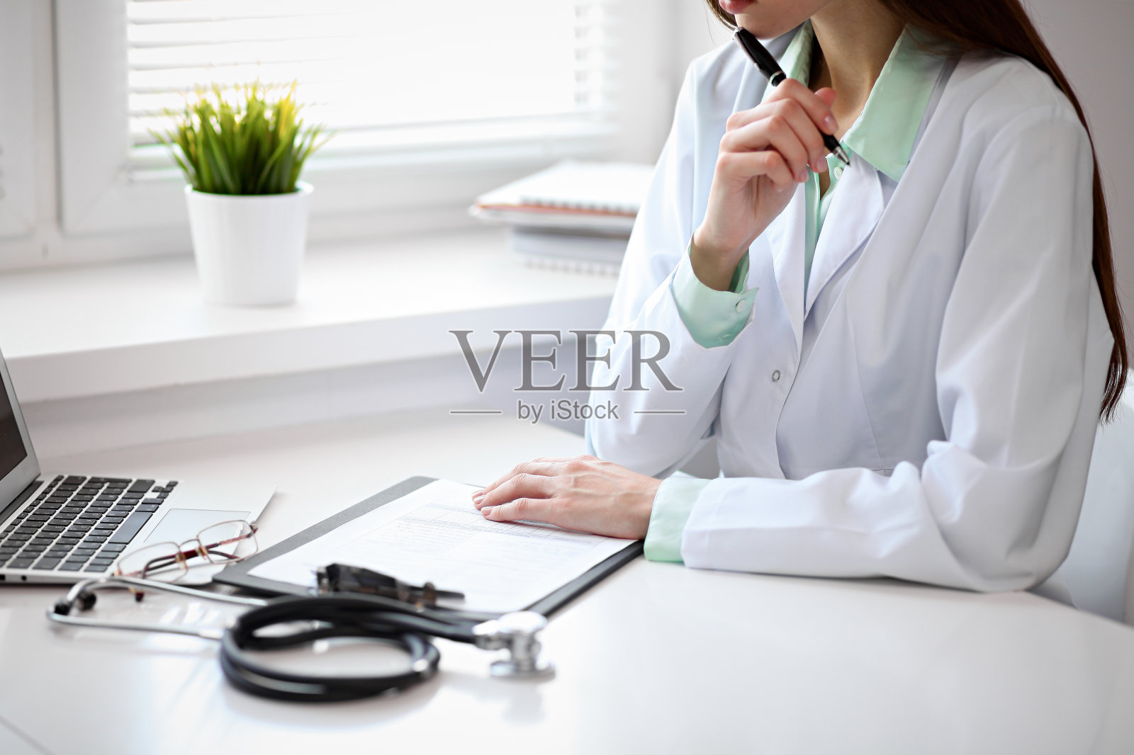 近距离观察未知女医生坐在靠近窗户的桌子在医院照片摄影图片