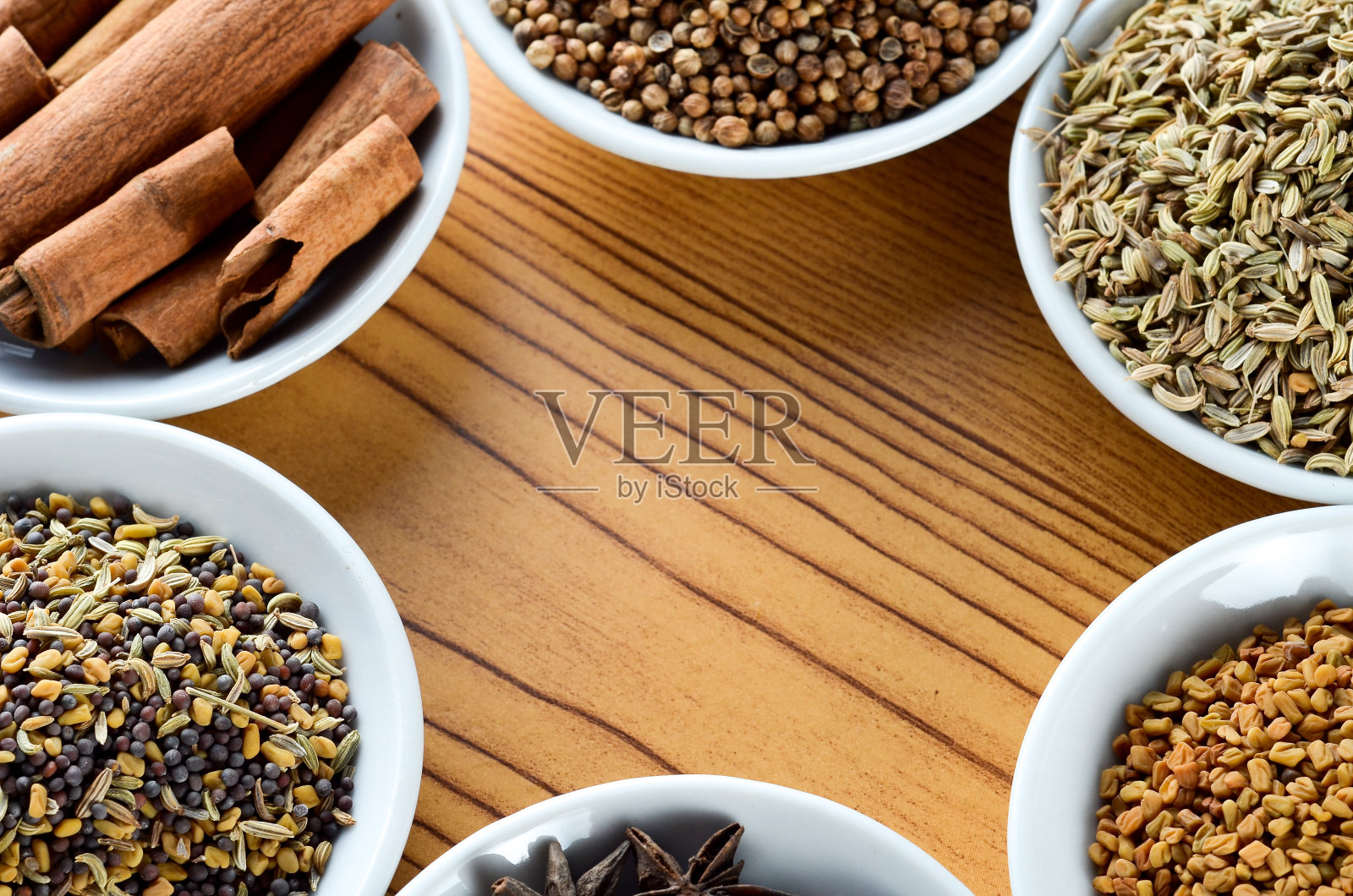 混合香料八角，茴香，肉桂，葫芦巴在碗的木制背景创造了文本空间的框架照片摄影图片