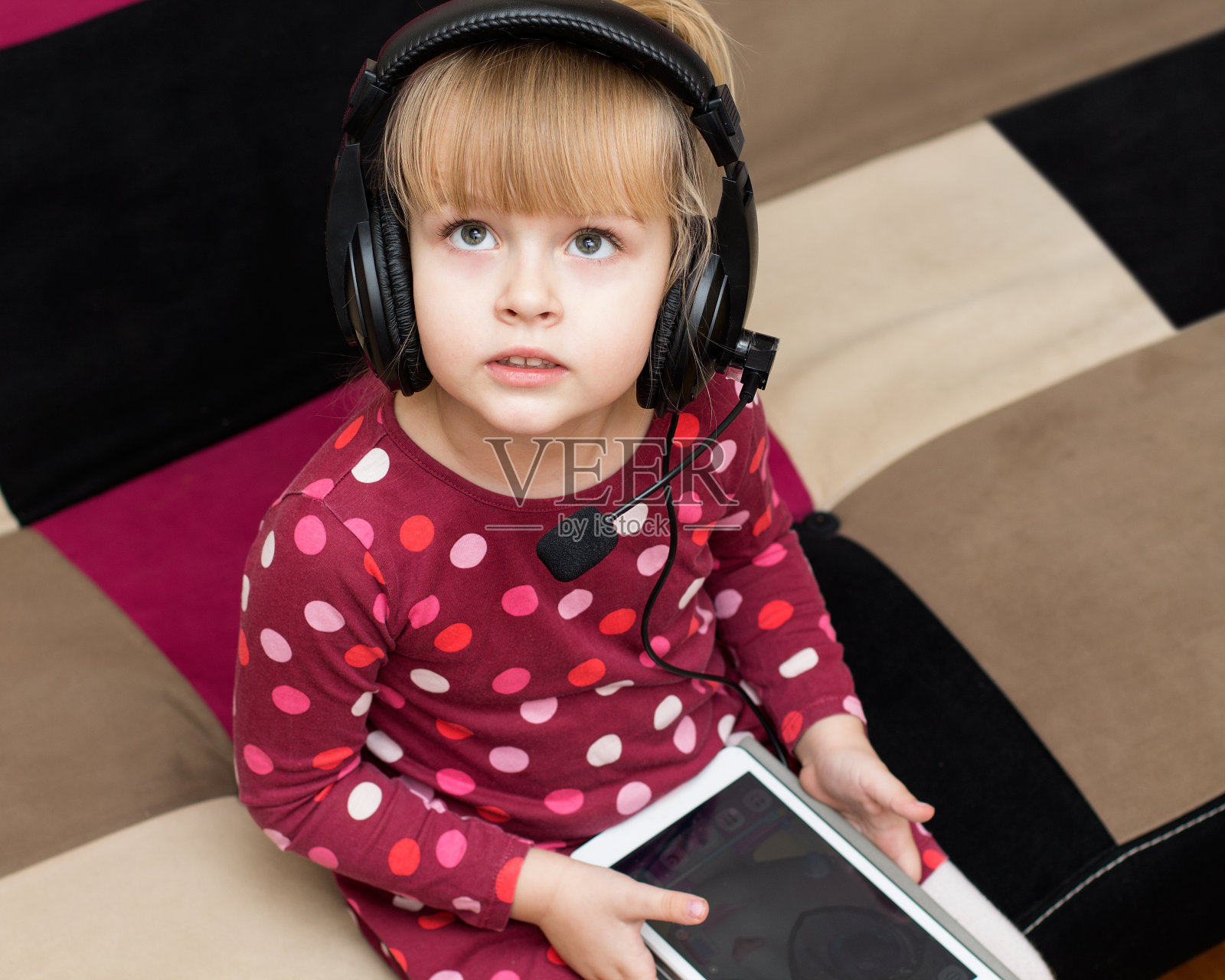 小女孩戴着耳机拿着平板电脑照片摄影图片