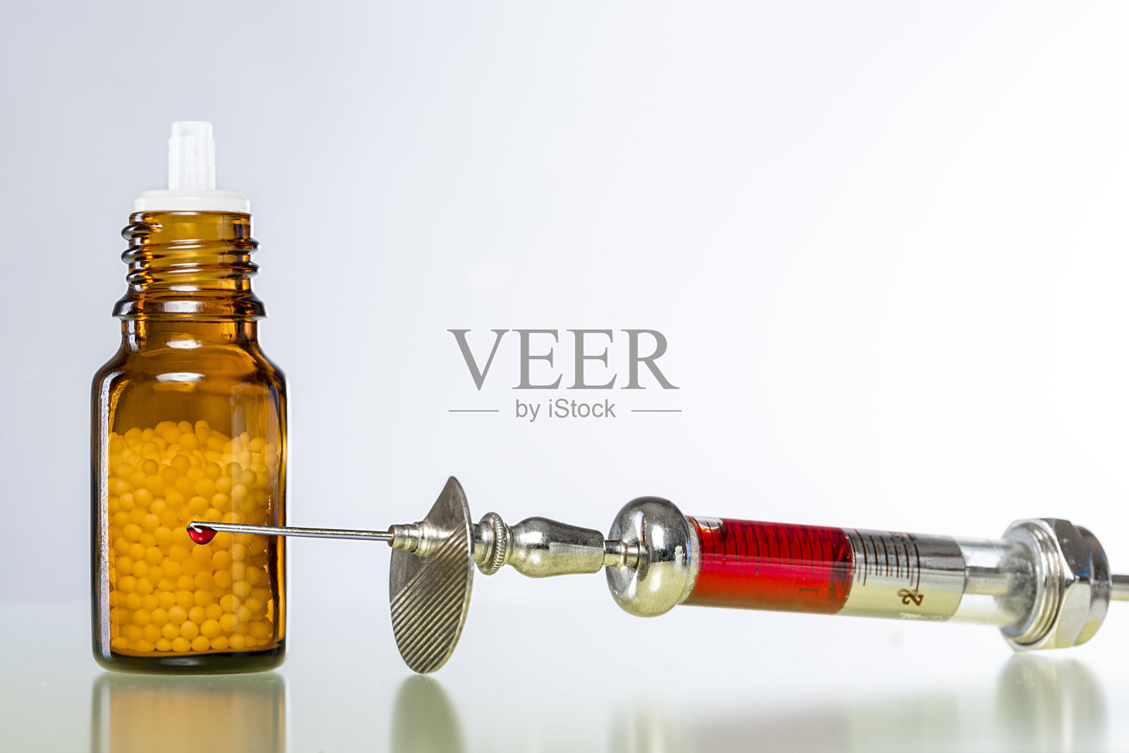 有顺势疗法液滴和血液注射器的静物照片摄影图片
