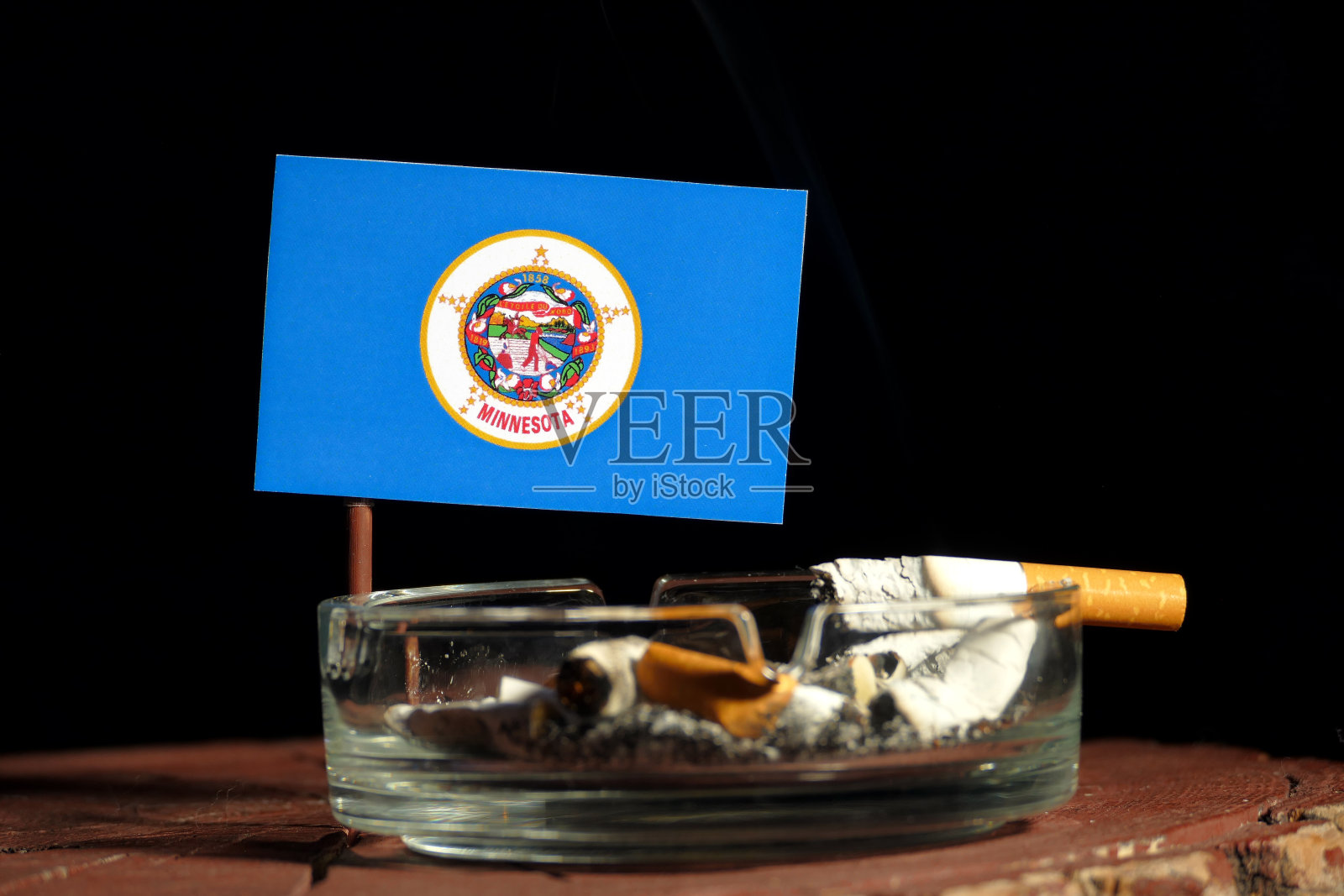 在黑色背景下，烟灰缸中燃烧着的香烟照片摄影图片