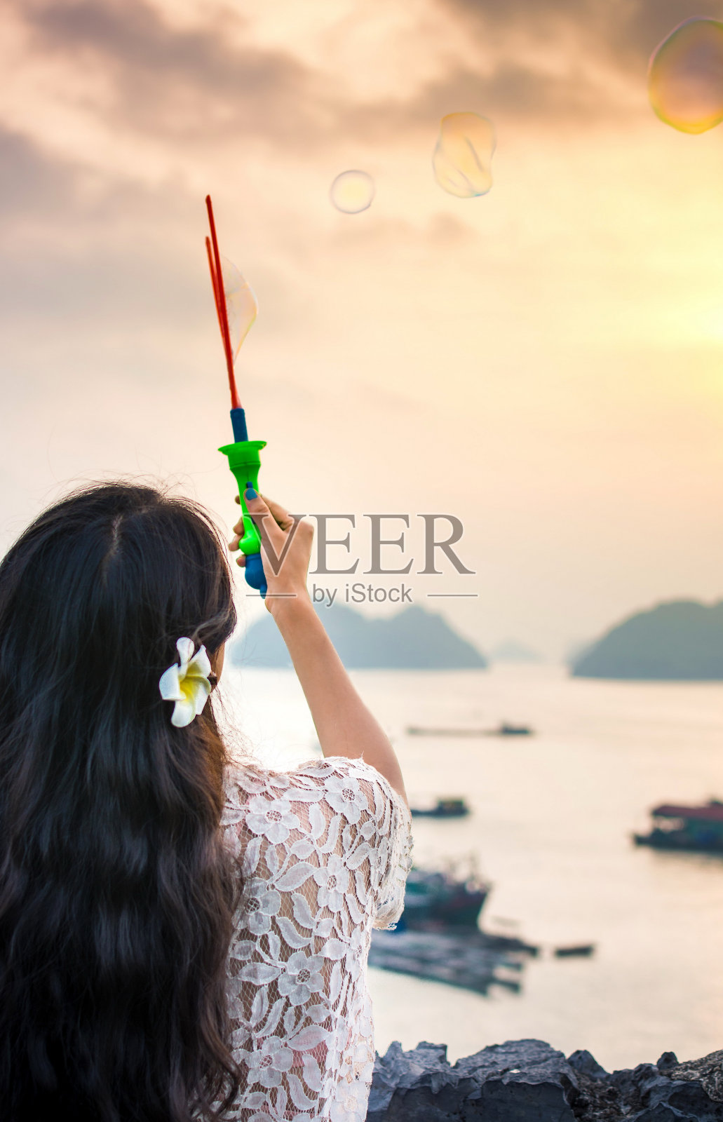 日落时分，女孩在海边吹肥皂泡照片摄影图片