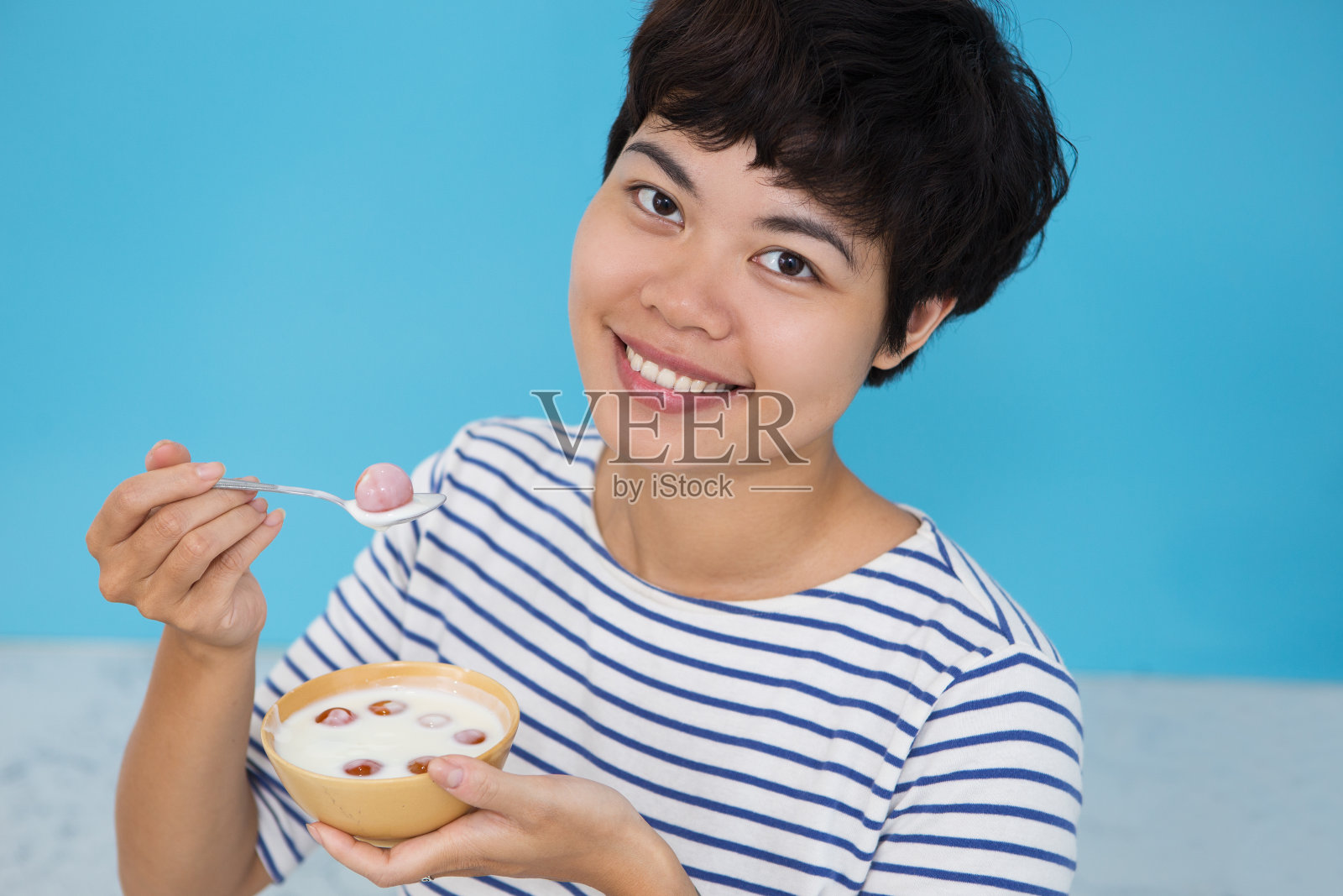 快乐的年轻亚洲女人吃西红柿照片摄影图片