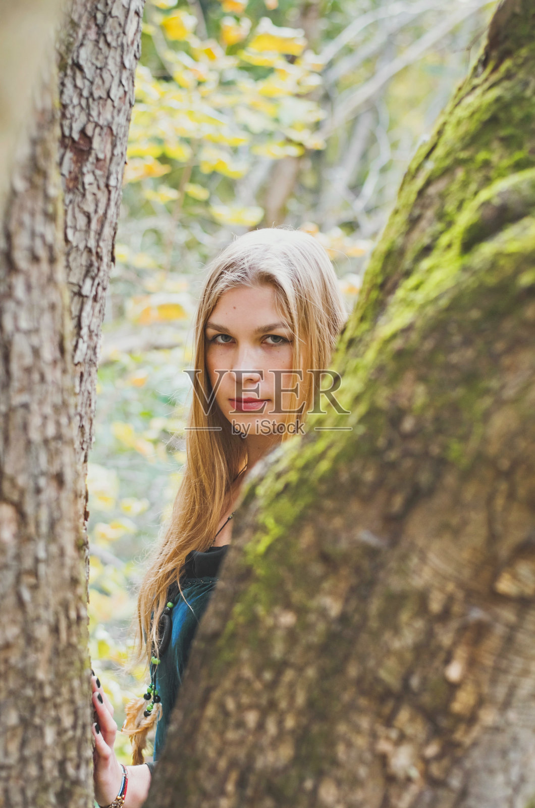 金色长发的女孩穿着梦幻般的黑色连衣裙在秋天的森林里，恐怖的万圣节童话照片摄影图片
