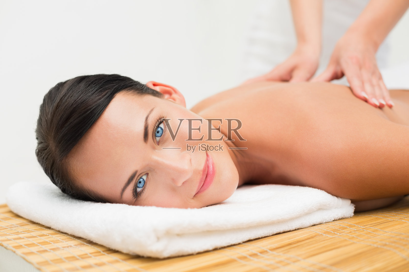 美丽的黑发女子享受背部按摩微笑在镜头照片摄影图片